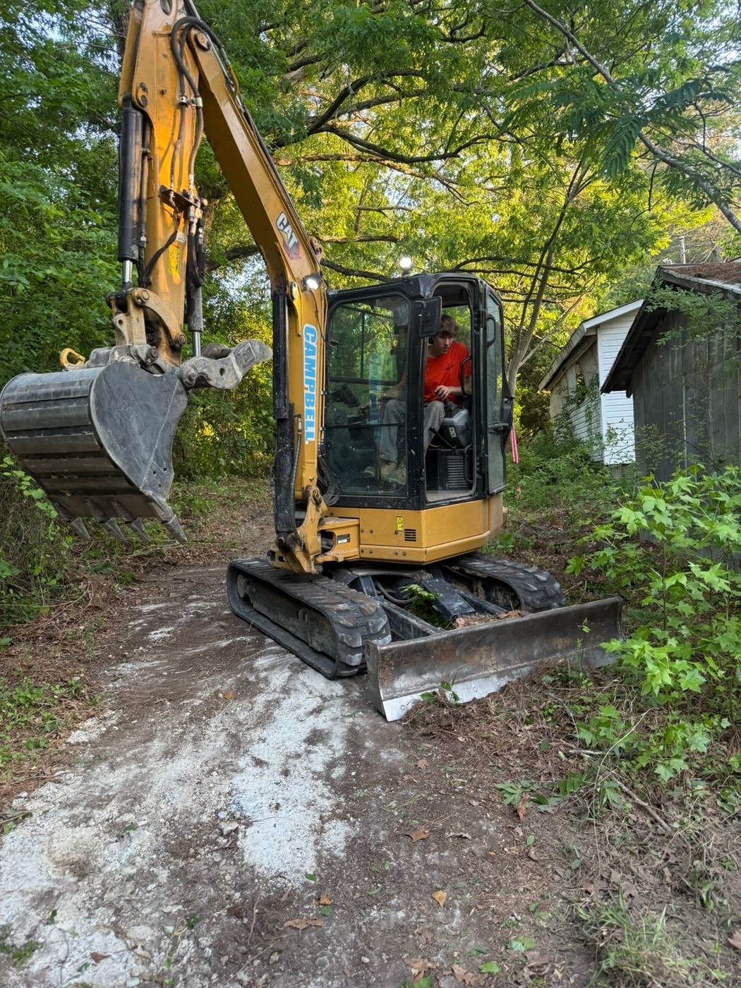 Clearing an overgrown access path between outbuildings.