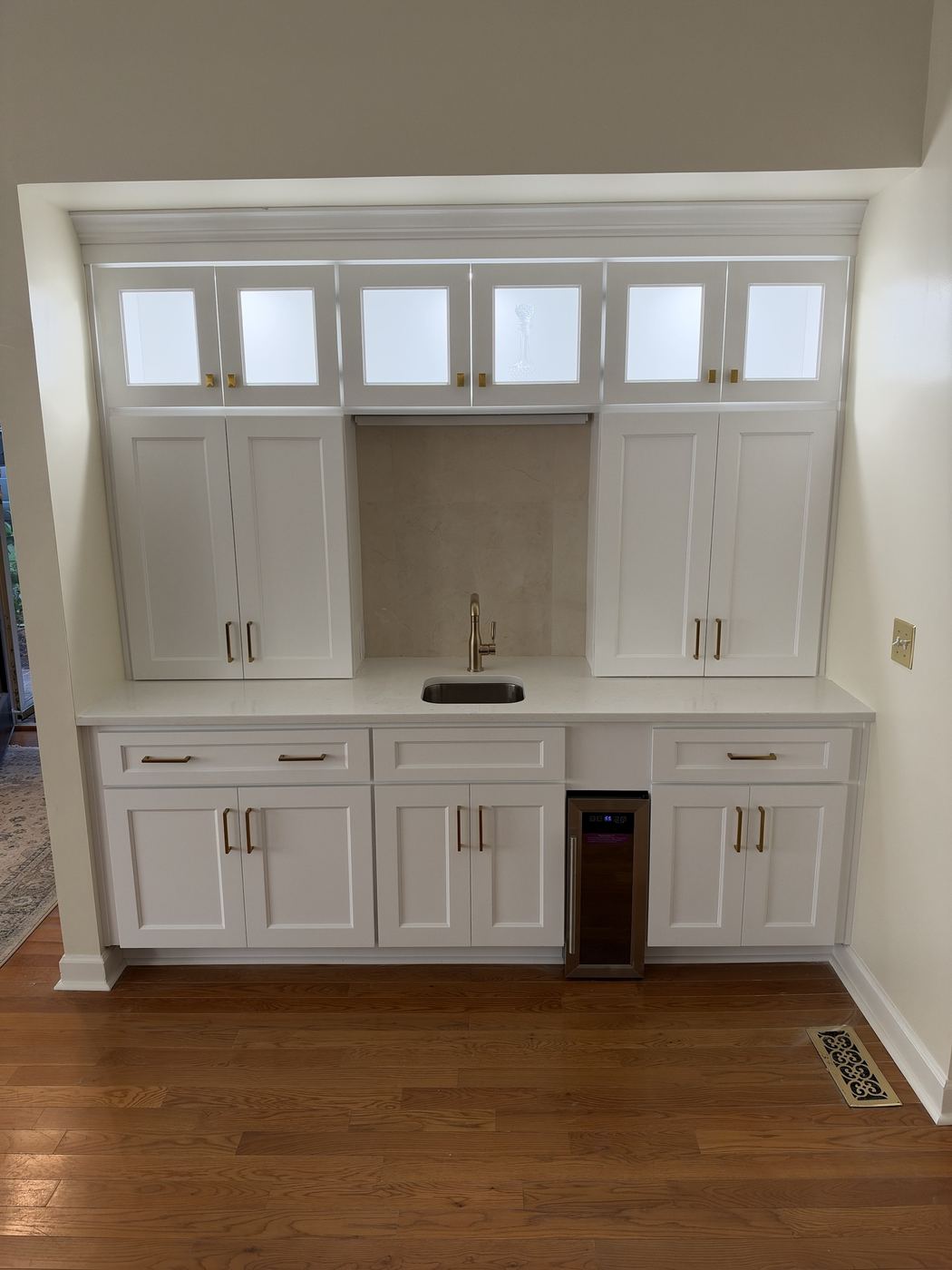 Wet bar with glass-front uppers, quartz top, and a wine fridge.