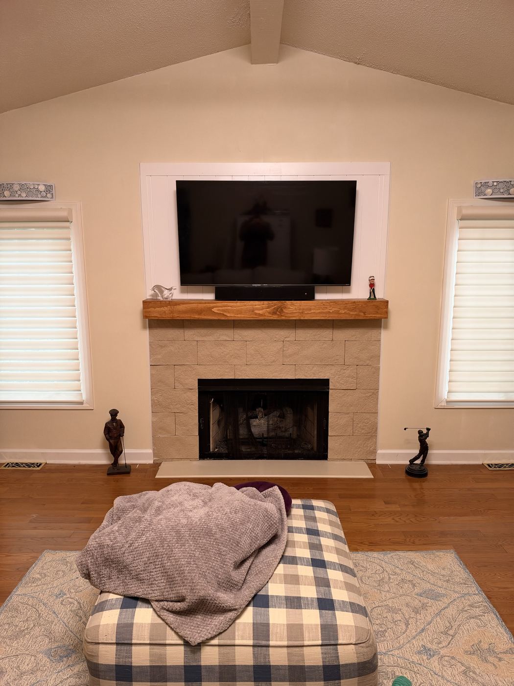 New wood mantel, stone surround, and a paneled TV wall above.