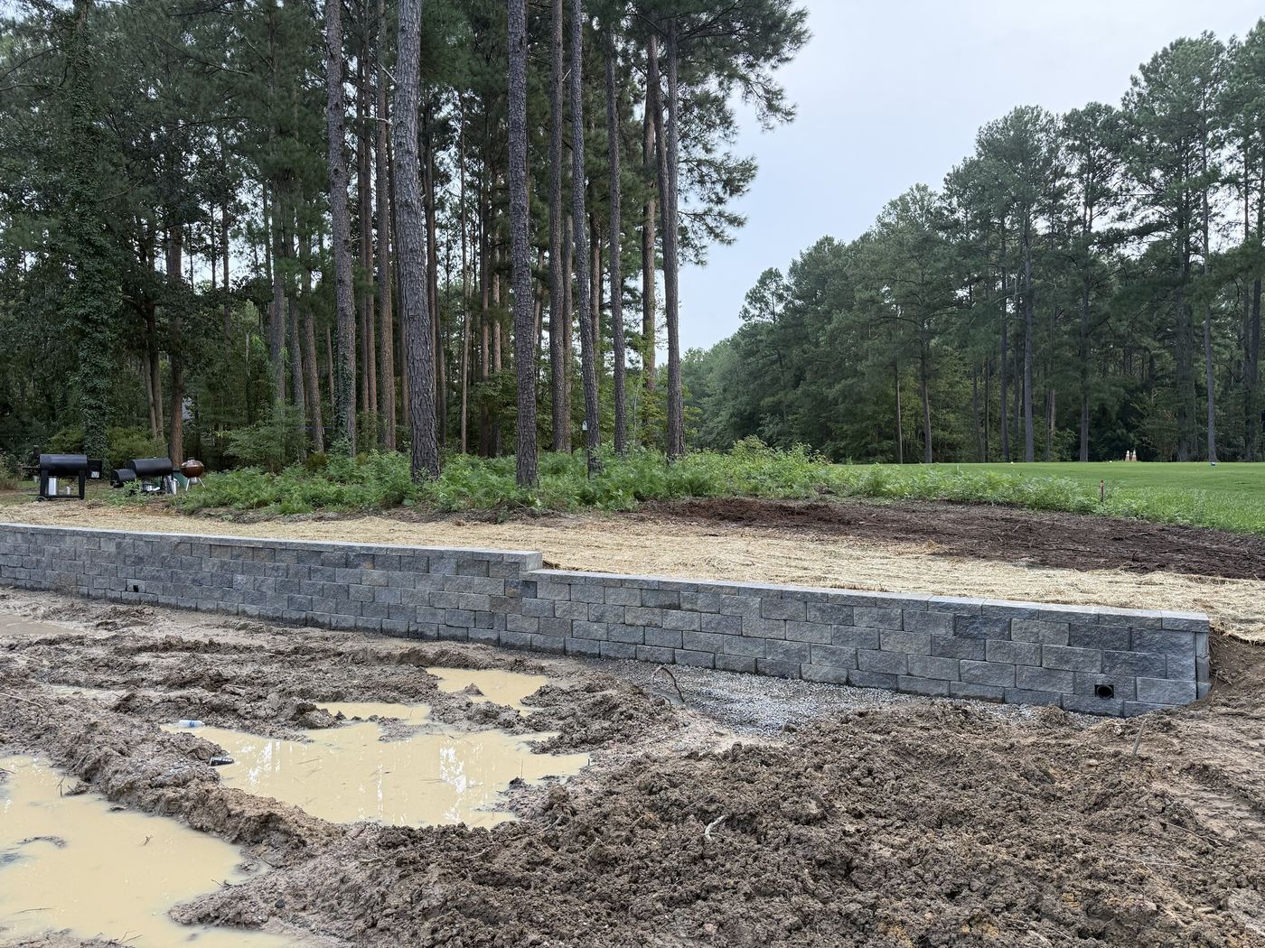 Stepped retaining wall on a gravel base, with straw down on the graded yard above.