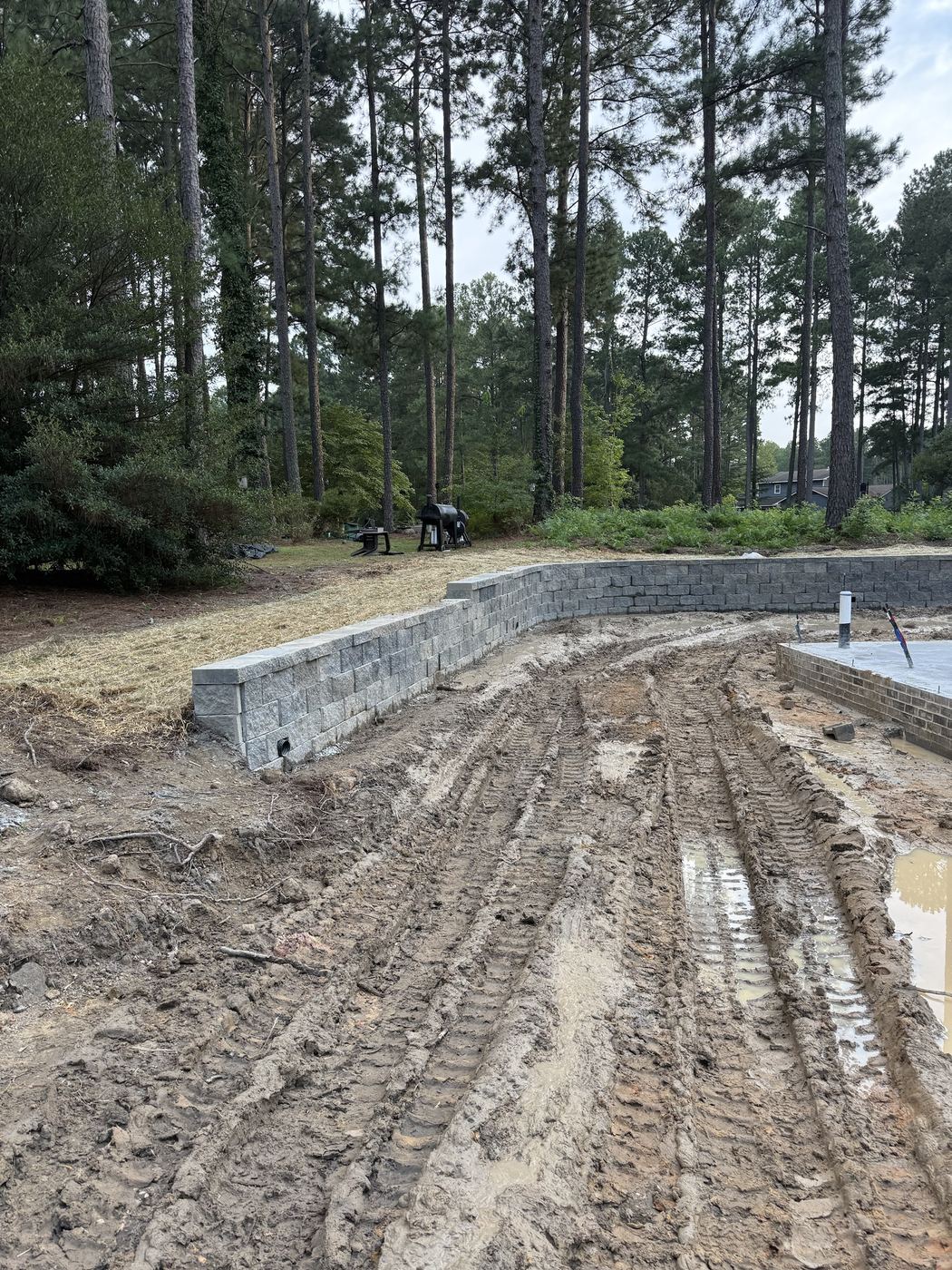Curved block wall holding back the upper yard, with weep drains at the bottom course.